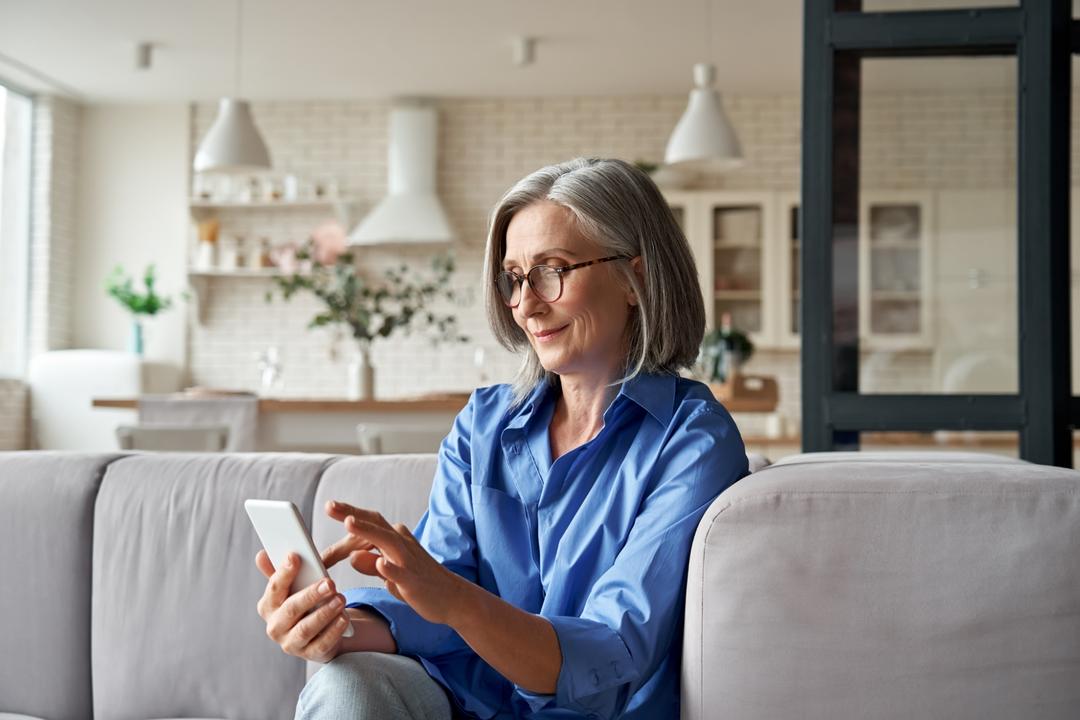Woman on sofa at home using mobile phone.